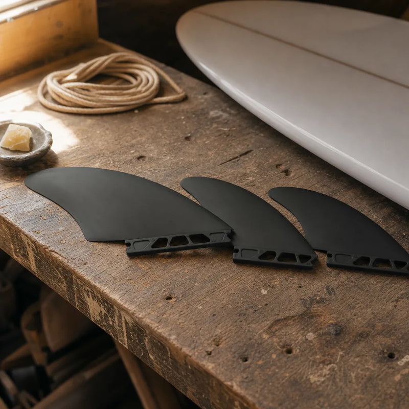 STCo. Future Composite Basic Keel Fins – Black styled on a shaping bench (AI-generated visualization)